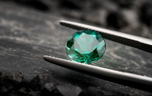 The emerald gemstone jewelry cut with dark stone background.