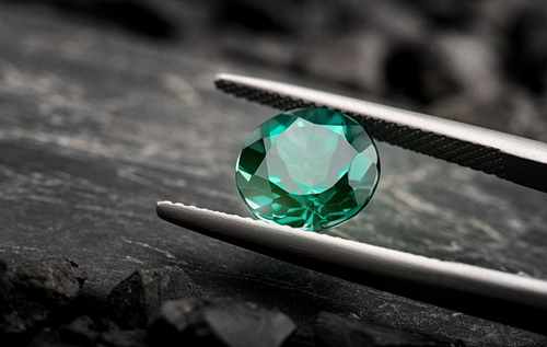 The emerald gemstone jewelry cut with dark stone background.