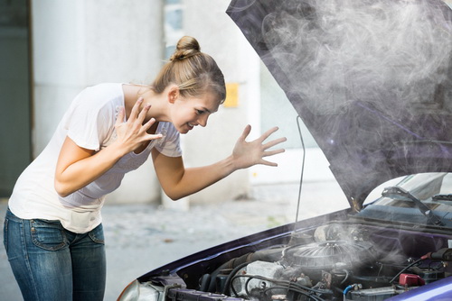 Woman looking at an overheated car